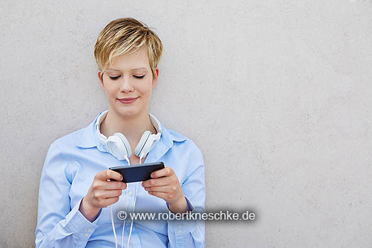 Junge Frau mit Kopfhörer nutzt Smartphone